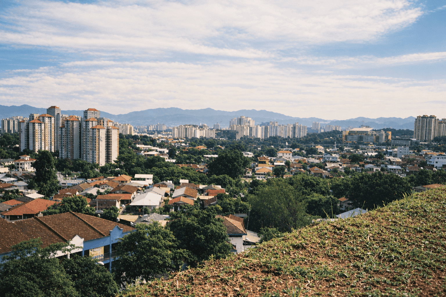 View across the low-rise housing of Salak Selatan, Kuala Lumpur, towards distant high-rise blocks and hills