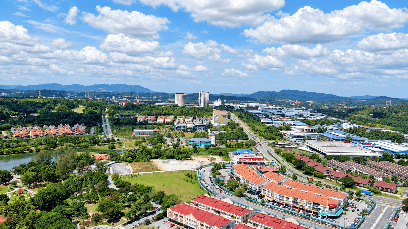 Aerial view of Bangi, Selangor, showing a lake and parkland beside rows of orange-roofed shophouses and terraced homes, with hills on the horizon